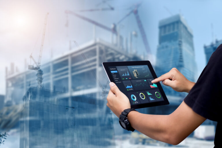 A man holds a tablet computer, overseeing construction work in the background, showcasing modern technology in the field.